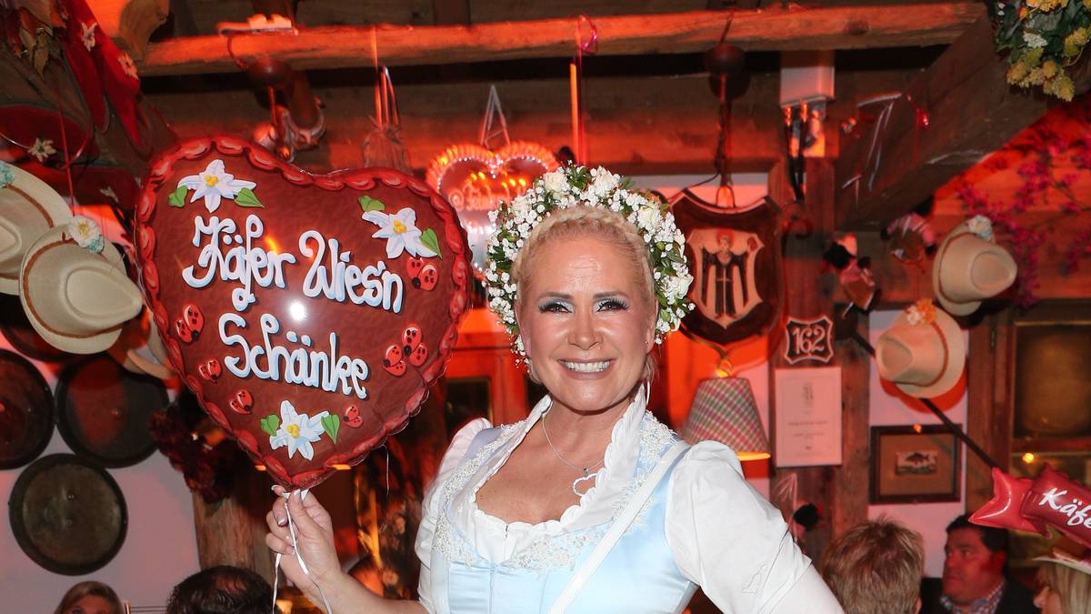 Claudia Effenberg grinst mitsamt Blumenkopfschmuck in die Kamera