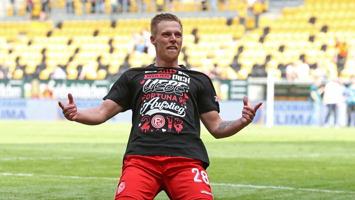 Auf dem Spielfeld brechen alle Dämme. Aufstiegsheld Hennings rutscht auf den Knien im Aufstiegs-T-Shirt Richtung Fans