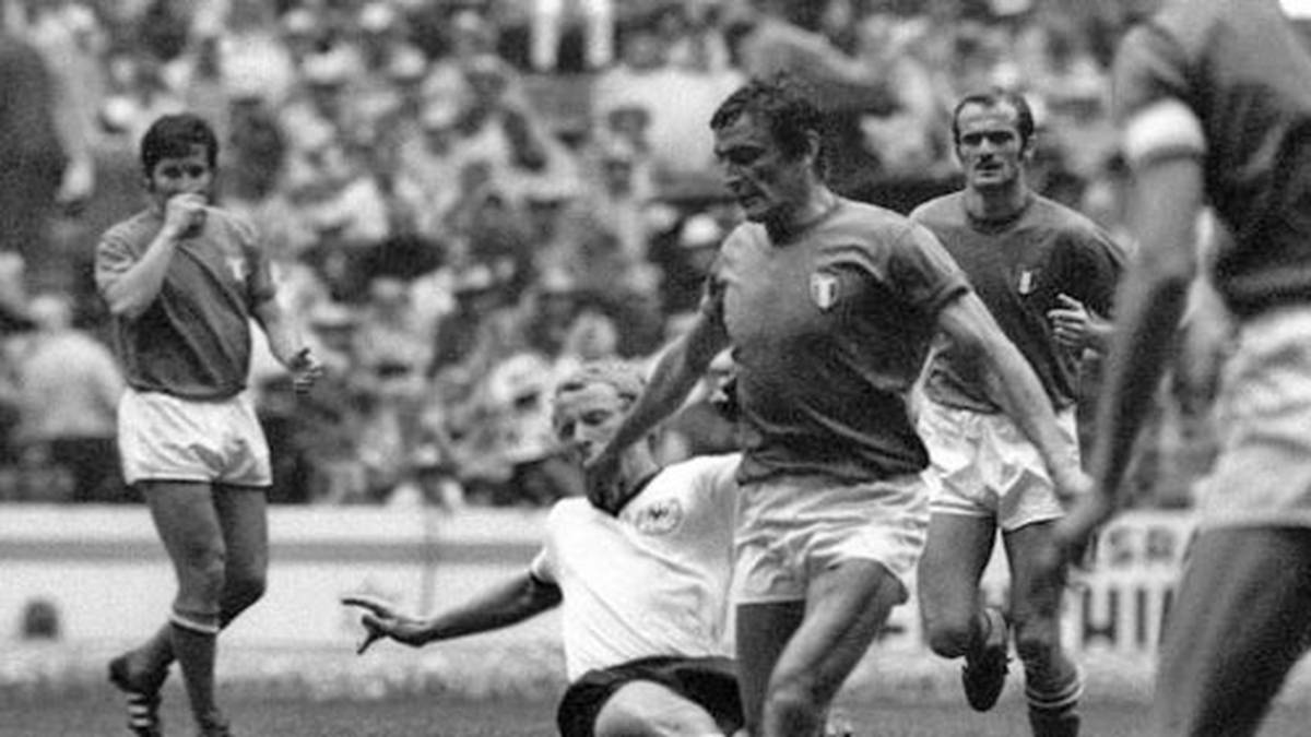 Bei unmenschlichen 50 Grad kommen beide Teams im Halbfinale nur langsam in Fahrt. 102.444 Zuschauer fiebern dem ersten Tor entgegen, aber zunächst regiert die harte Hand. Berti Vogts (u.) zeigt, warum er Terrier genannt wird und rasiert Luigi Riva