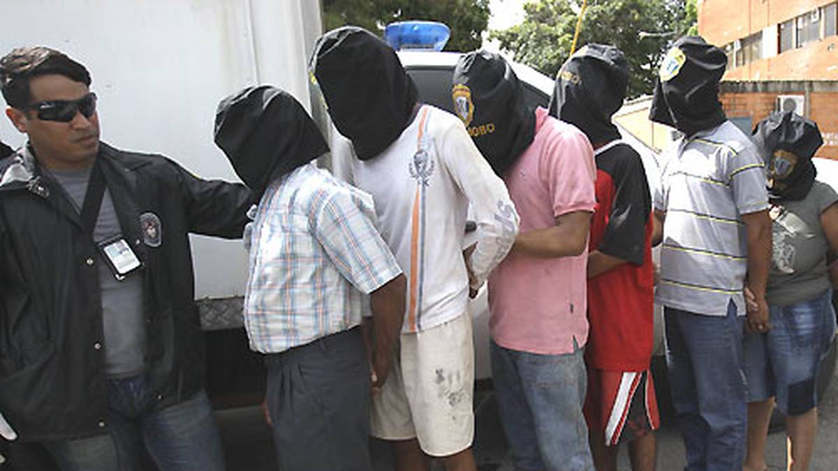 Die mutmaßlichen Entführer werden der Menge mit verdeckten Gesichtern zur Schau gestellt