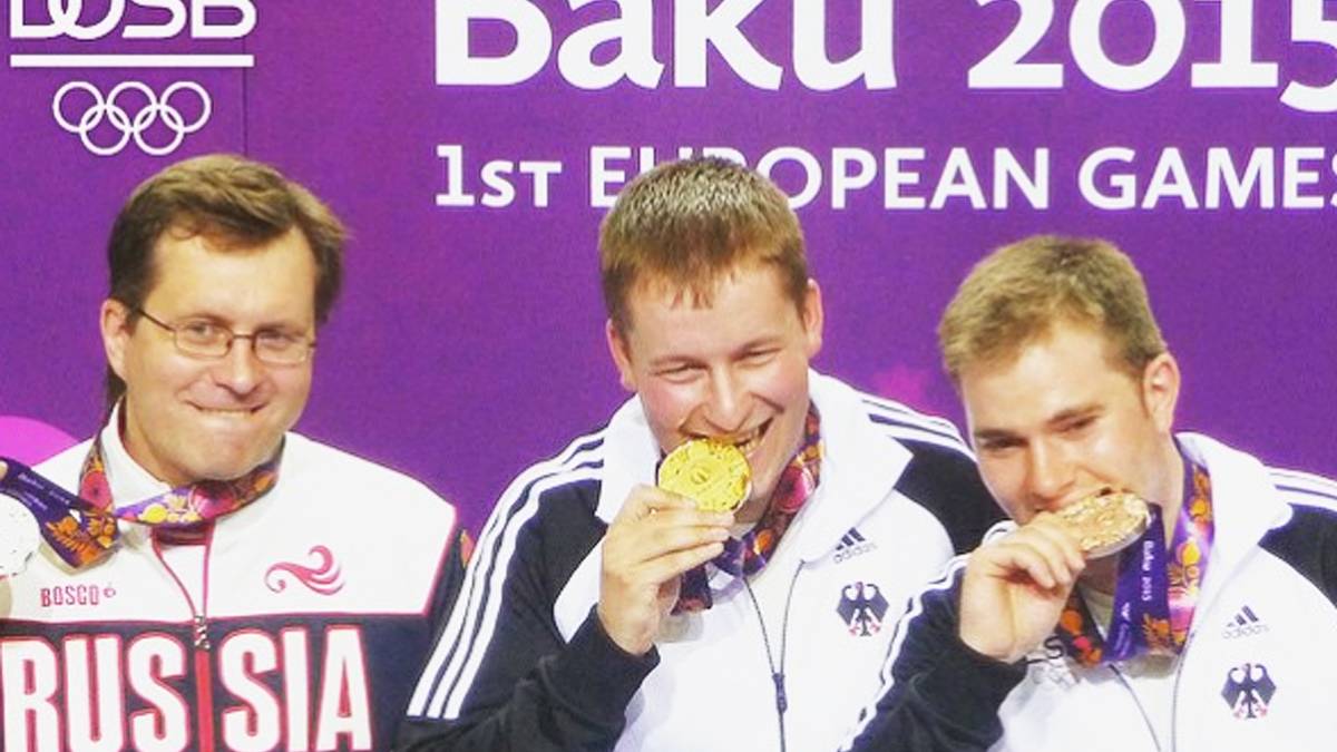 Die Schützen Christian Reitz (mitte) und Oliver Geis unterziehen ihre Medaillen dem Bisstest