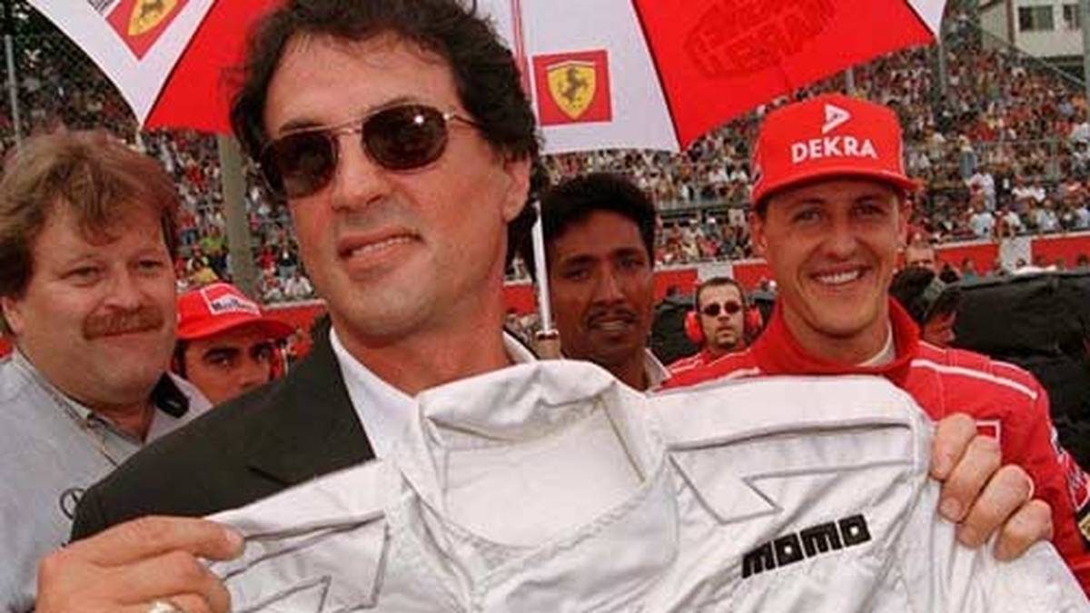 Monza zieht in jedem Jahr auch Stars aus anderen Unterhaltungsbrachen an. Hier posiert Sylvester Stallone mit einem Mercedes-Rennanzug. Im Hintergrund scheinen sich Norbert Haug (l.) und Michael Schumacher darüber zu amüsieren
                  