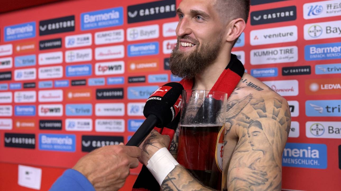 Mood in Leverkusen: Robert Andrich gibt in der Mixed Zone ein Interview mit einem sehr großen Bierglas