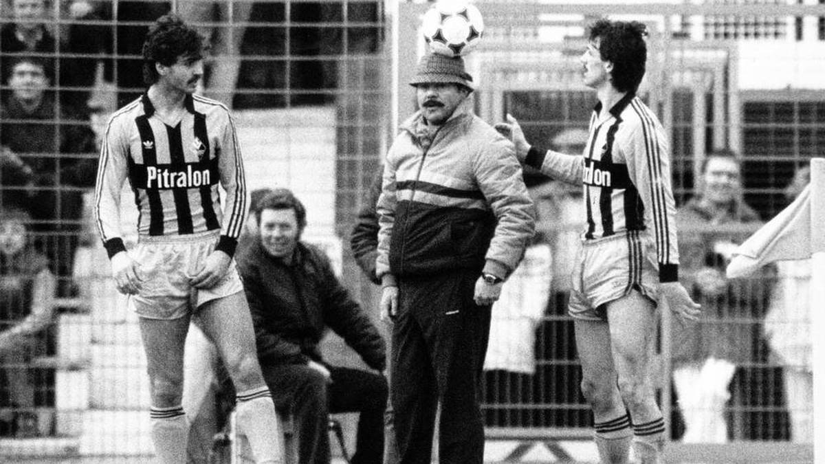 Waldhof-Mannheim-Trainer Klaus Schlappner (M.) trägt den Ball als Hut, daneben erstaunt er damit Jürgen Kohler (r.) und Maurizio Gaudino