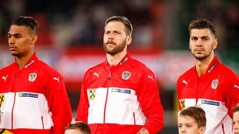 VIENNA, AUSTRIA - MARCH 29:  Rubin Okotie, Guido Burgstaller and Aleksandar Dragovic of Austria (L-R) line up during the national anthem prior to the international friendly match between Austria and Turkey at Ernst-Happel-Stadium on March 29, 2016 in Vienna, Austria. (Photo by Christian Hofer/Getty Images)