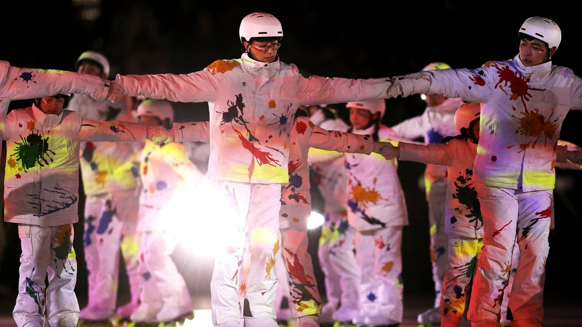 In farbig bemalten Anzügen laufen "Skifahrer" in das Stadion ein