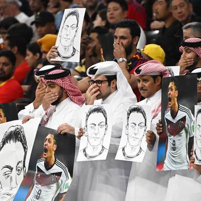 Während des DFB-Spiels gegen Spanien zeigen einige Zuschauer Plakate mit dem Konterfei von Ex-Nationalspieler Mesut Özil. Dabei halten sie sich die Münder zu wie bereits das DFB-Team.