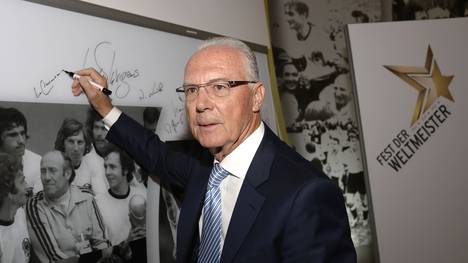 Franz Beckenbauer unterschreibt auf einer Wand