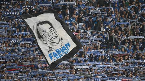 Eine große Fahne mit dem Bild des verstorbenen Fans wird im Schalker Fanblock geschwenkt