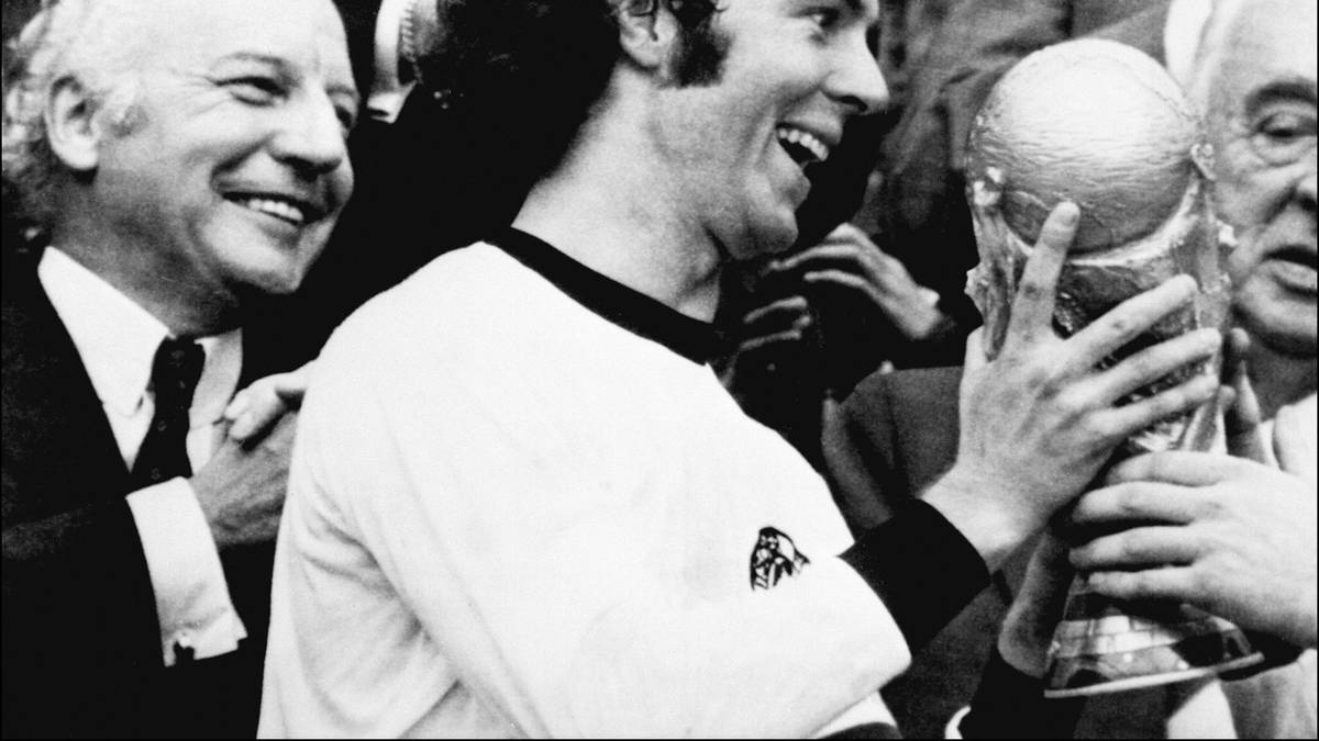 Franz Beckenbauer nahm bei der Heim-WM 1974 den WM-Pokal noch im schlichten weißen Shirt mit schwarzem Kragen in Empfang.