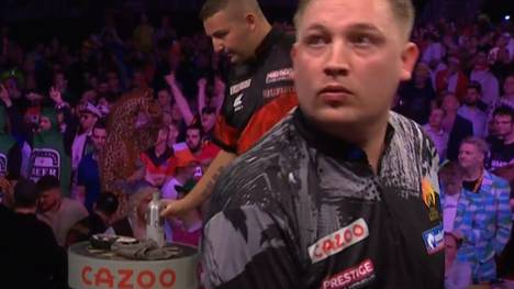 Bei der Premier League of Darts springt ein Bouncer sehr nahe an Chris Dobey, der davon sichtlich irritiert wirkt. 