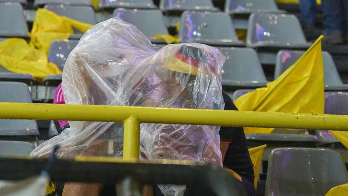 Zwei Fans bringen sich unter einer Plane in Sicherheit. 