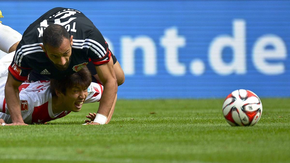 Beide Teams kämpfen mit Haken und Ösen. Kölns Yuya Osako wird von Leverkusens Ömer Toprak auf den Rasen gedrückt