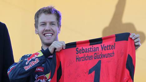 Germany's Sebastian Vettel holds up a je