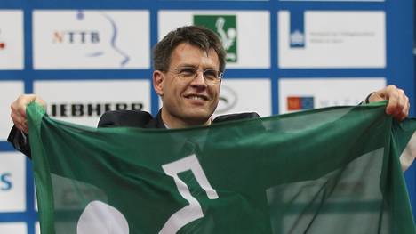 Thomas Weikert hält eine Fahne des ITTF in der Hand