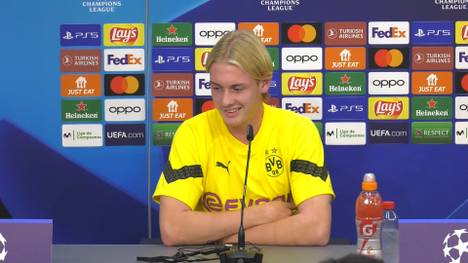 Julian Brandt wird vor dem Spiel gegen Sevilla nach den Unterschieden zwischen Modeste und Haaland gefragt. Der Name des Neuzugangs führt allerdings zu Verwirrung beim Dolmetscher. 