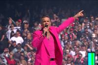 Beim Rugby AFL Grand Final sorgt ein Star-Gast für gute Stimmung. Der komplett in rosa gekleidete Robbie Williams heizt mit einem Medley der Rugby-Meute an.