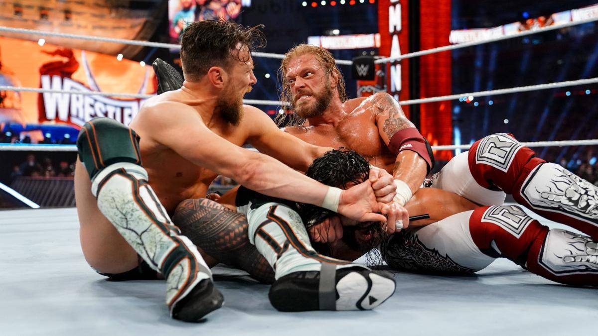Roman Reigns (M.) wird bei WWE WrestleMania 37 von Daniel Bryan und Edge in die Zange genommen