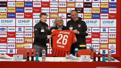 Auf der Pressekonferenz vor dem Spiel gegen Eintracht Frankfurt sorgt Frank Schmidt für einen besonderen Moment. Der Trainer des 1. FC Heidenheim verschenkt ein Trikot an einen Reporter, der seine letzte Pressekonferenz begleitet.