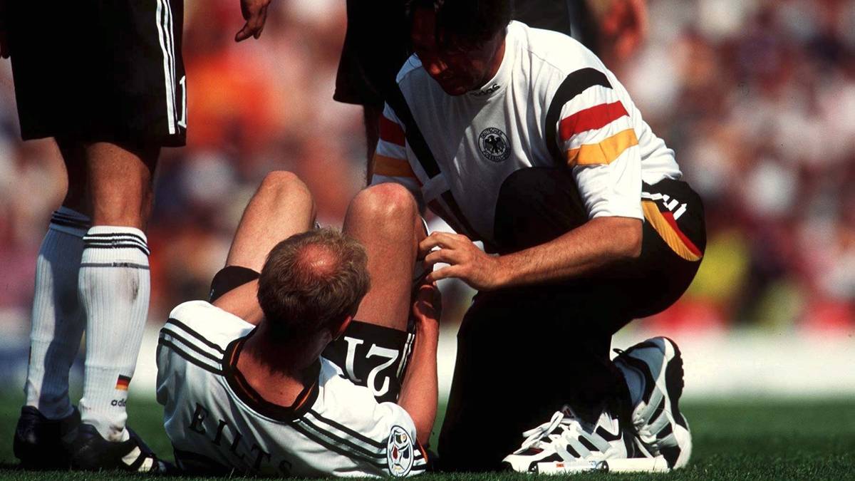 Seit 1995 war Müller-Wohlfahrt auch Teamarzt der deutschen Nationalmannschaft. Gleich bei seinem ersten großen Turnier 1996 wird Deutschland mit ihm in England Europameister. Hier kümmert sich Müller-Wohlfahrt im Gruppenspiel gegen Italien um Malocher Dieter Eilts