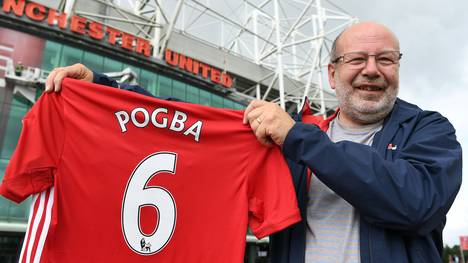 Ein Mann präsentiert stolz sein neues Trikot von Paul Pogba