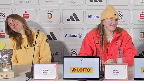 Die deutschen Olympia-Athletinnen Julia Taubitz, Emma Aicher und Kira Weidle-Winkelmann werden auf einer Pressekonferenz zu ihrem Maskottchen befragt - daraufhin bricht Gelächter aus.