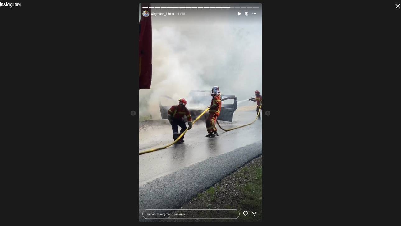 Feuerwehrleute löschen das brennende Polizeiauto