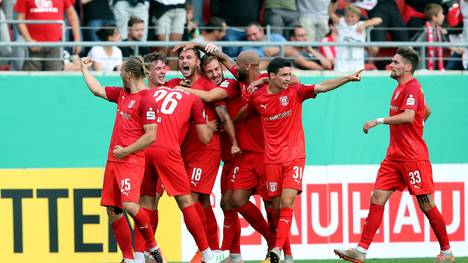 HALLE, GERMANY - AUGUST 12: Felix Drinkuth (#18) of Hallescher FC celebrates after scoring the 1-0 lead with team mates during the DFB Cup first round match between Hallescher FC and VfL Wolfsburg at Erdgas-Sportpark on August 12, 2019 in Halle, Germany. (Photo by Ronny Hartmann/Bongarts/Getty Images)