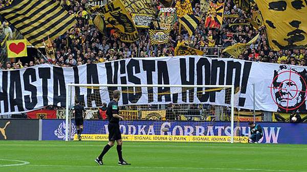 Vor dem Spiel gibt es eine äußert unschöne Aktion: Dietmar Hopps Konterfei versehen die Fans von Borussia Dortmund mit einer Zielscheibe und schreiben "Hasta la Viste, Hopp"