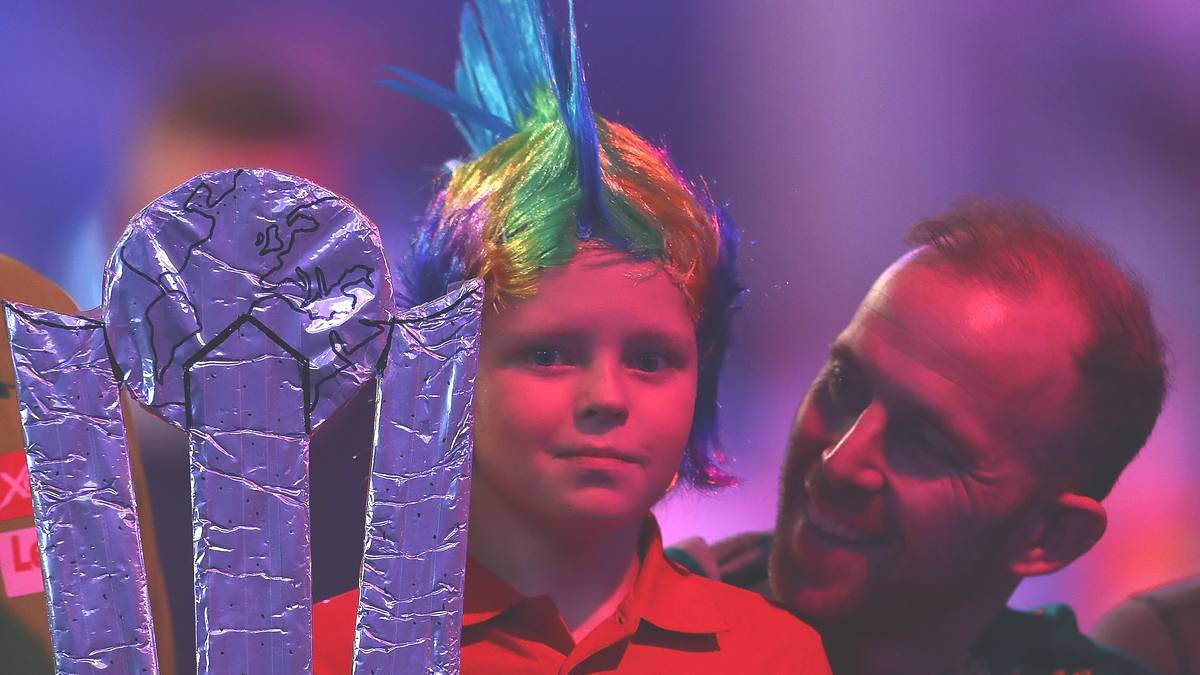 Wer Vorbild dieses jungen Fans ist, ist nicht schwer zu erraten. Den Kopf des Knaben schmückt eine Perücke im Stil von Peter Wright. Dem Schotten würde sicherlich gefallen, was auf dem Schild des Jungen steht... 