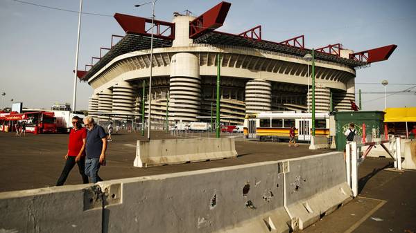 People walk past concrete barriers placed at the entrance of the Giuseppe Meazza Stadium in Milan on August 27, 2017. / AFP PHOTO / Marco BERTORELLO        (Photo credit should read MARCO BERTORELLO/AFP/Getty Images)