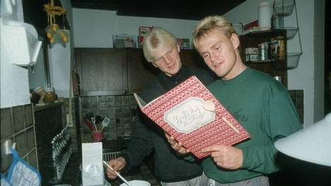 Stefan Effenberg und Joerg Neun mit Kochbuch am Herd 