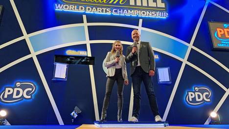 Jana Wosnitza (l.) und Hartwig Thöne berichteten in der Anfangsphase der Darts-WM für SPORT1 aus London