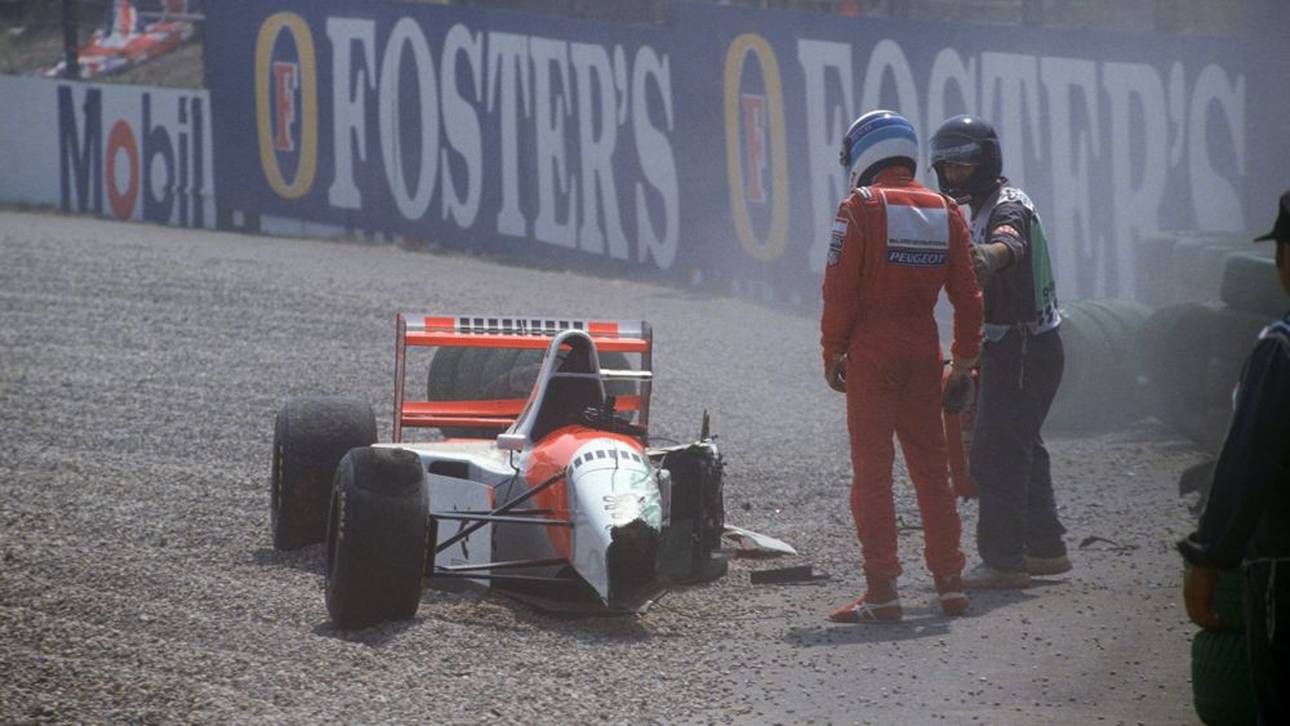 Mika Häkkinen (rot) steht neben seinem verunfallten Wagen.