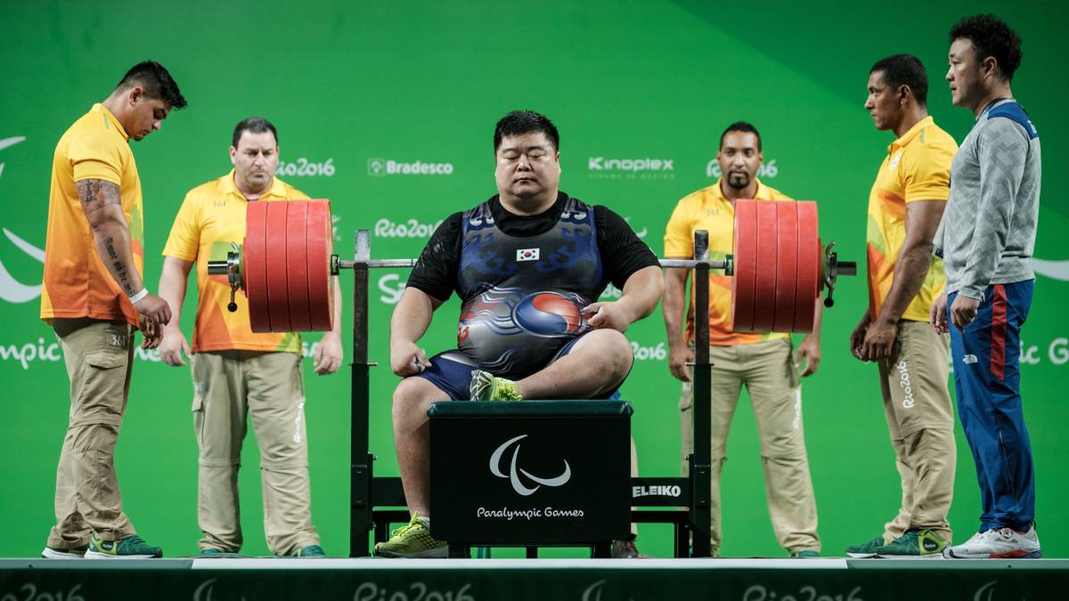 Mehrere Helfer sind nötig, um dem südkoreanischen Gewichtheber Keun Bae Chun die Langhantel reichen zu können