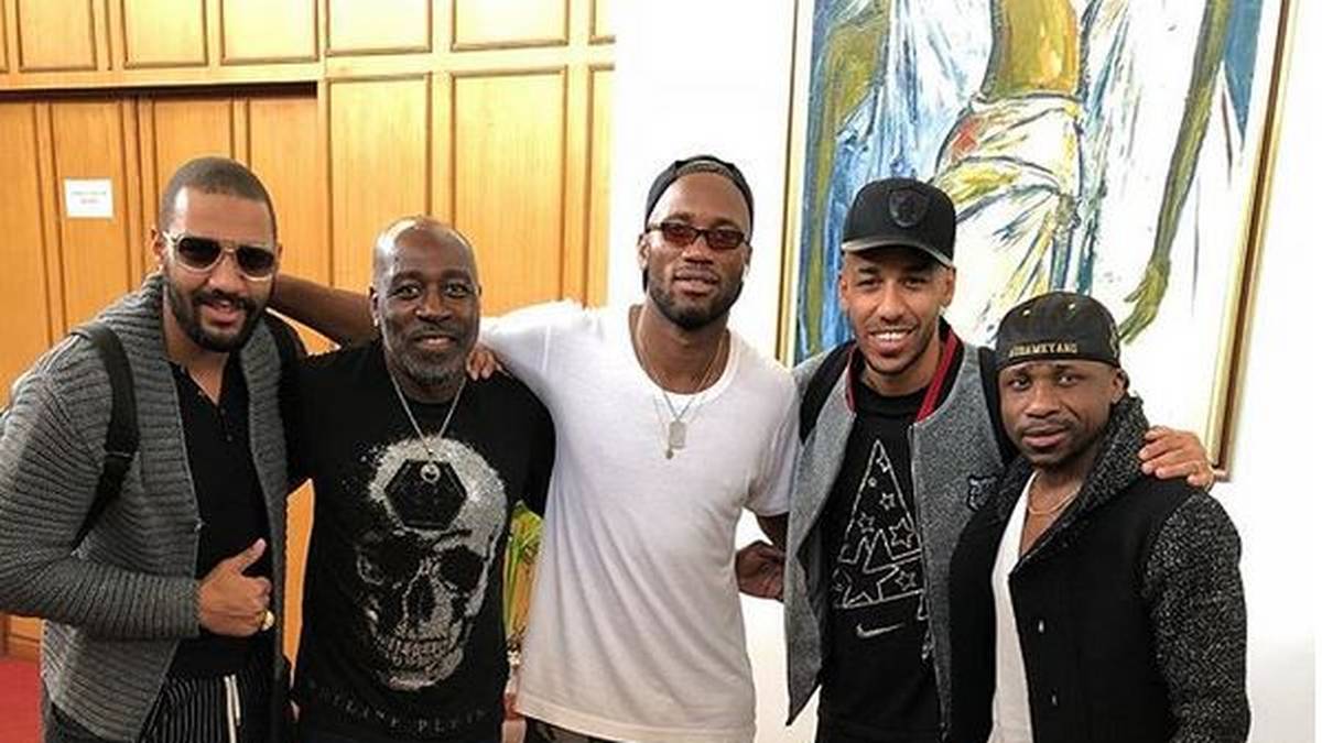 JANUAR 2018: Kurz nach einem Treffen mit Superstar Didier Drogba (M.) begleiten Aubameyangs Vater Pierre Francois (2.v.l.) und Bruder Willy (l.) Pierre-Emerick ins Trainingslager nach Marbella - und checken im Mannschaftshotel ein