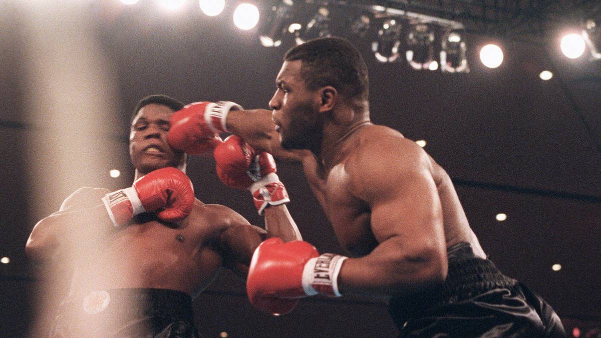 TYSON VS. BERBICK: Am 22. November 1986 wird Mike Tyson im Alter von 20 Jahren und 144 Tagen mit einem K.o.-Sieg in der zweiten Runde über WBC-Weltmeister Trevor Berbick der jüngste Schwergewichtsweltmeister der Geschichte. Nur drei Monate nach dem Gewinn seines ersten WM-Gürtels kann Tyson auch den Titel der WBA erringen
