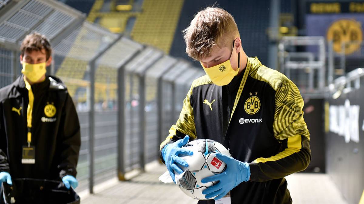 Der Balljunge der Partie Borussia Dortmund gegen Schalke 04 desinfiziert einen Spielball