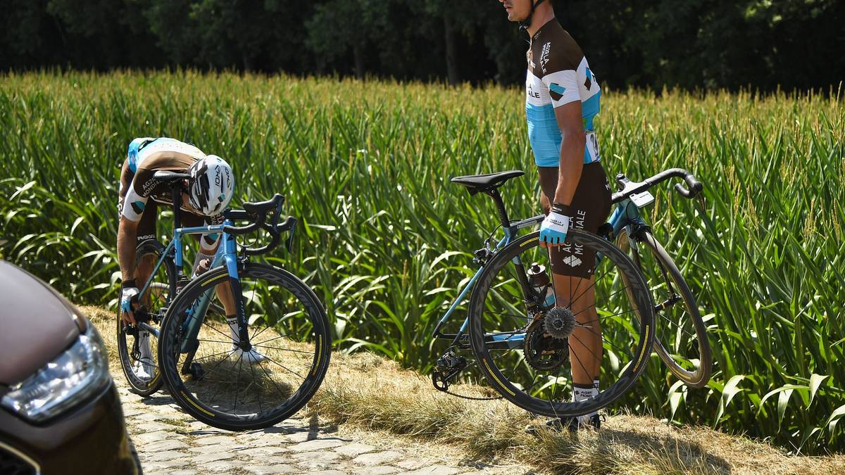 Den Fahrern wird alles abverlangt: Frankreichss Alexis Vuillermoz (r.) muss seinem Landsmann Romain Bardet zur Hand gehen, weil dieser einen platten Reifen ersetzen muss