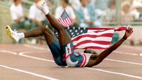 BARCELONA, SPAIN - AUGUST 6:  Kevin Young of the U.S. lies on the ground as he holds the American flag 06 August, 1992 in Barcelona shortly after winning the gold medal in the men's 400 meter hurdles with a world record setting time of 46.78 seconds.  (Photo credit should read MICHEL GANGNE/AFP/Getty Images)