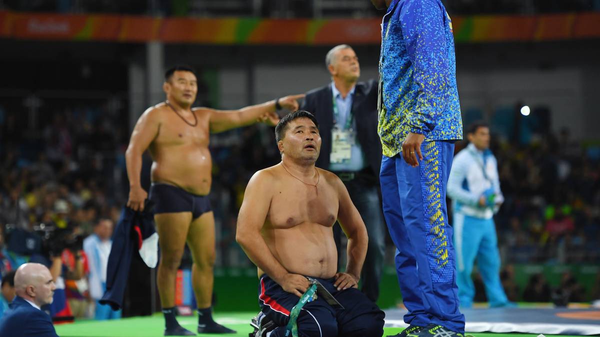 Bayaraa Byambarinchin und Tsogtbayar Tserenbaatar ziehen sich vor den Zuschauern aus und werfen ihre Bekleidung vor den Richtertisch