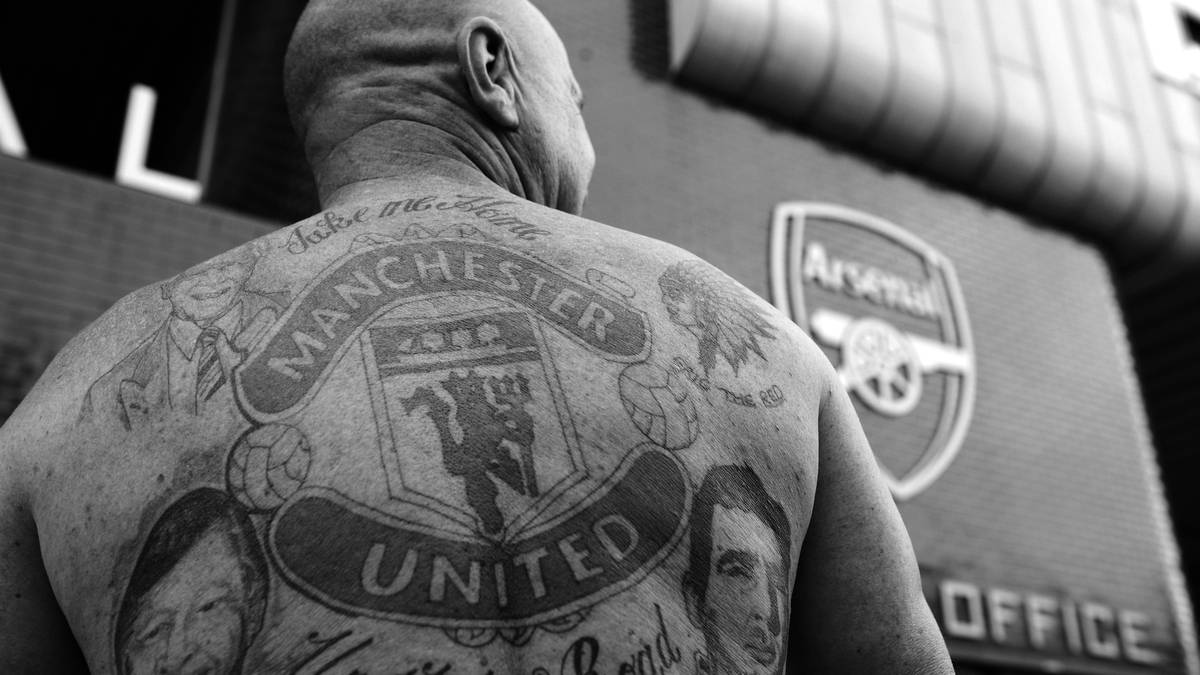 Man United zu Gast bei den Gunners. Den Rücken des United-Fans schmückt das zuletzt 1998 aktualisierte Vereinswappen. Seit Anfang der 70er Jahre hat es der Teufel mit Dreizack in das Logo der "Red Devils" geschafft. 1998 wurde im Logo "Football Club" durch den Schriftzug Manchester United ersetzt