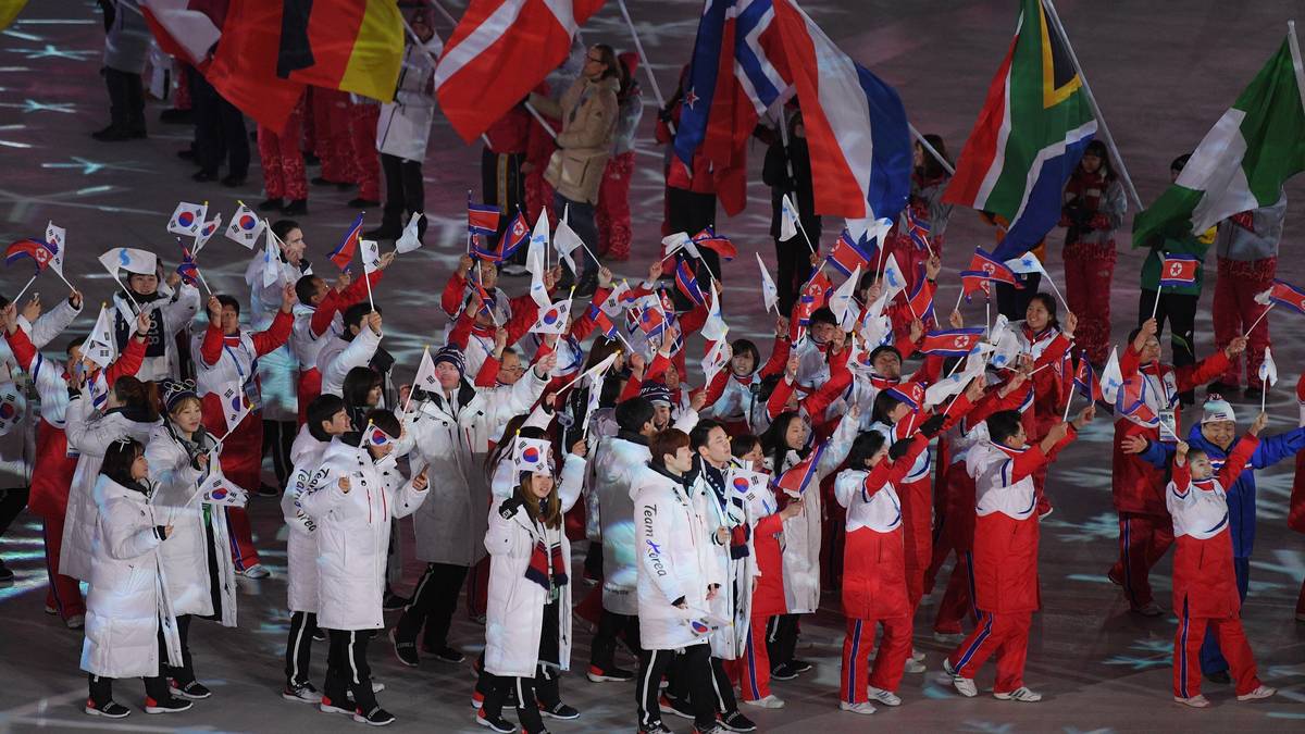 Während die Fahnenträger in der Mitte einen Kreis bilden laufen die Athleten außen herum. Für Deutschland trägt Eishockey-Profi Christian Ehrhoff die Fahne