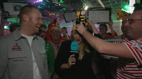 Die Party im Ally Pally ist wieder in vollem Gange. Mit kuriosen Kostümen präsentieren sich die Fans immer wieder und diesmal wurde Sport1-Moderatorin Katharina Kleinfeldt mit einbezogen.