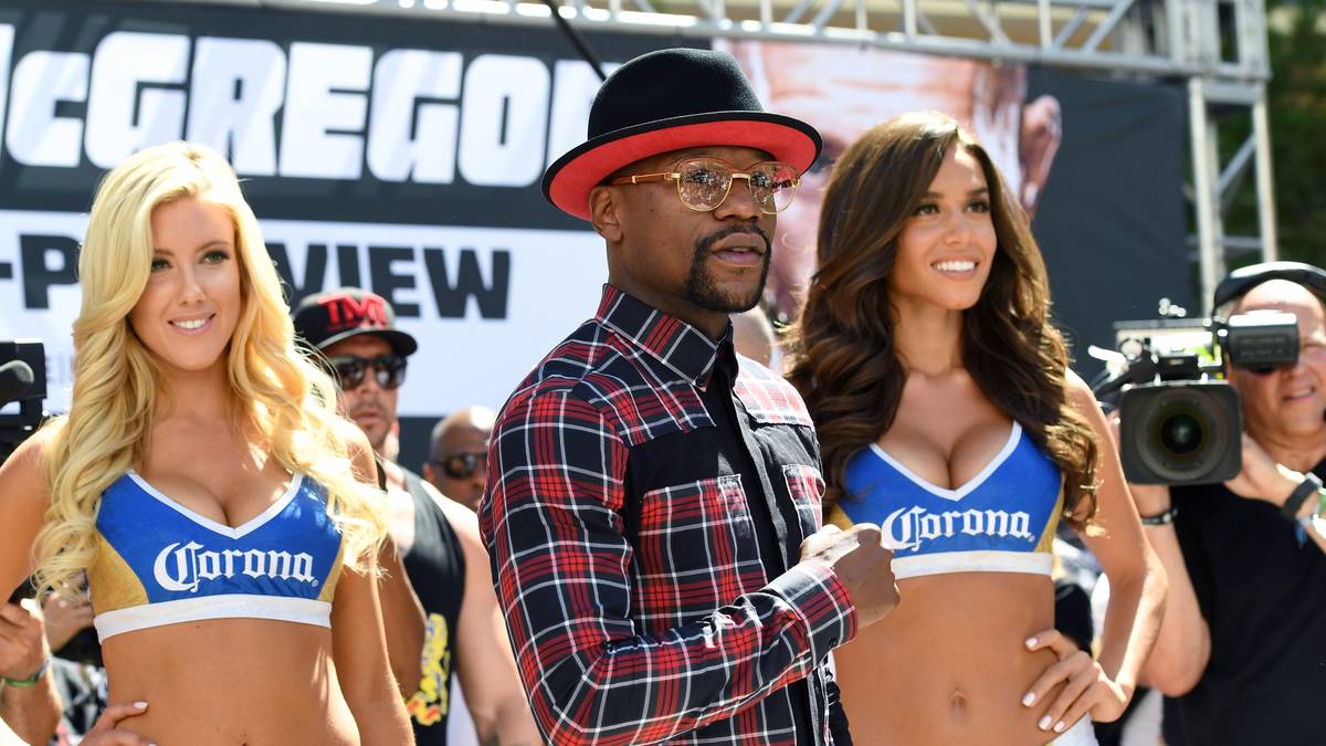Neben McGregor präsentiert sich auch Floyd Mayweather den Fans und der Presse. Dabei zeigt sich der Stripclub-Besitzer standesgemäß mit zwei leicht bekleideten Damen