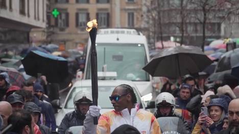Der US-Rapper Snoop Dogg wurde eingeladen, die olympische Fackel im Vorfeld der Winterspiele 2026 durch die Straßen Italiens zu tragen. Dabei wird er von Dutzenden begeisterten Fans begleitet.