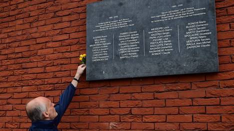 Ein Mann platziert eine Blume hinter eine Gedenkplatte für die Opfer der Heysel-Katastrophe