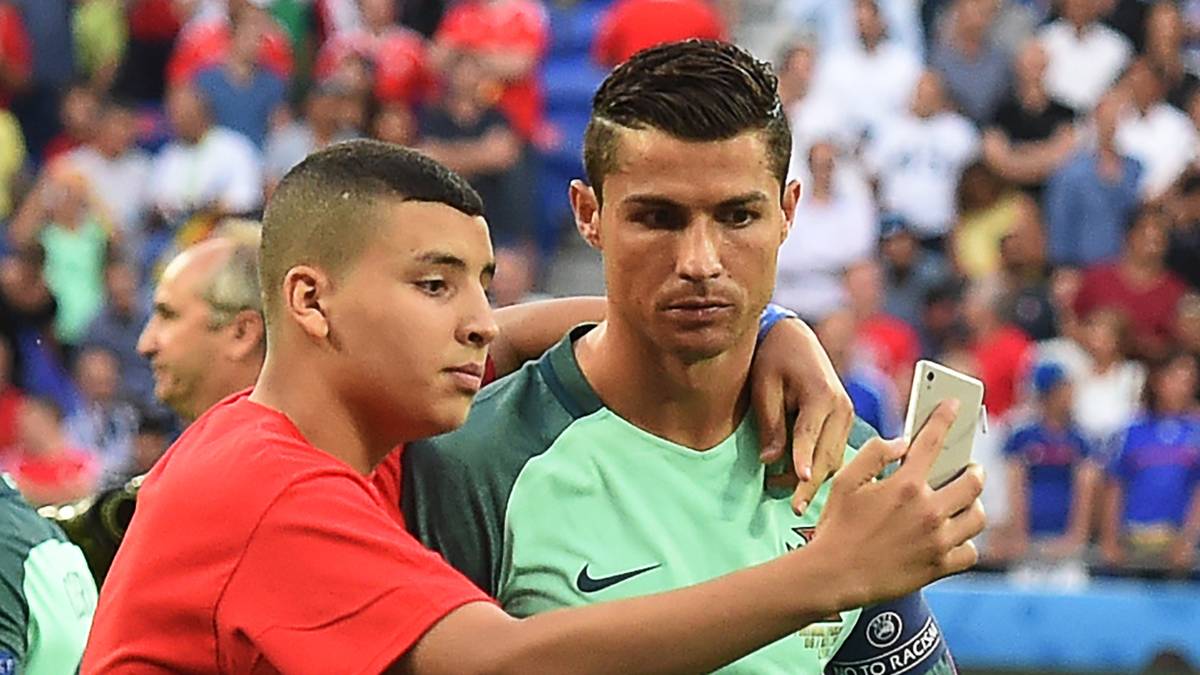 Ein Jugendlicher, der vor dem Spiel ein Teil der Choreografie auf dem Rasen ist, staubt danach noch ein Selfie mit Cristiano Ronaldo ab
