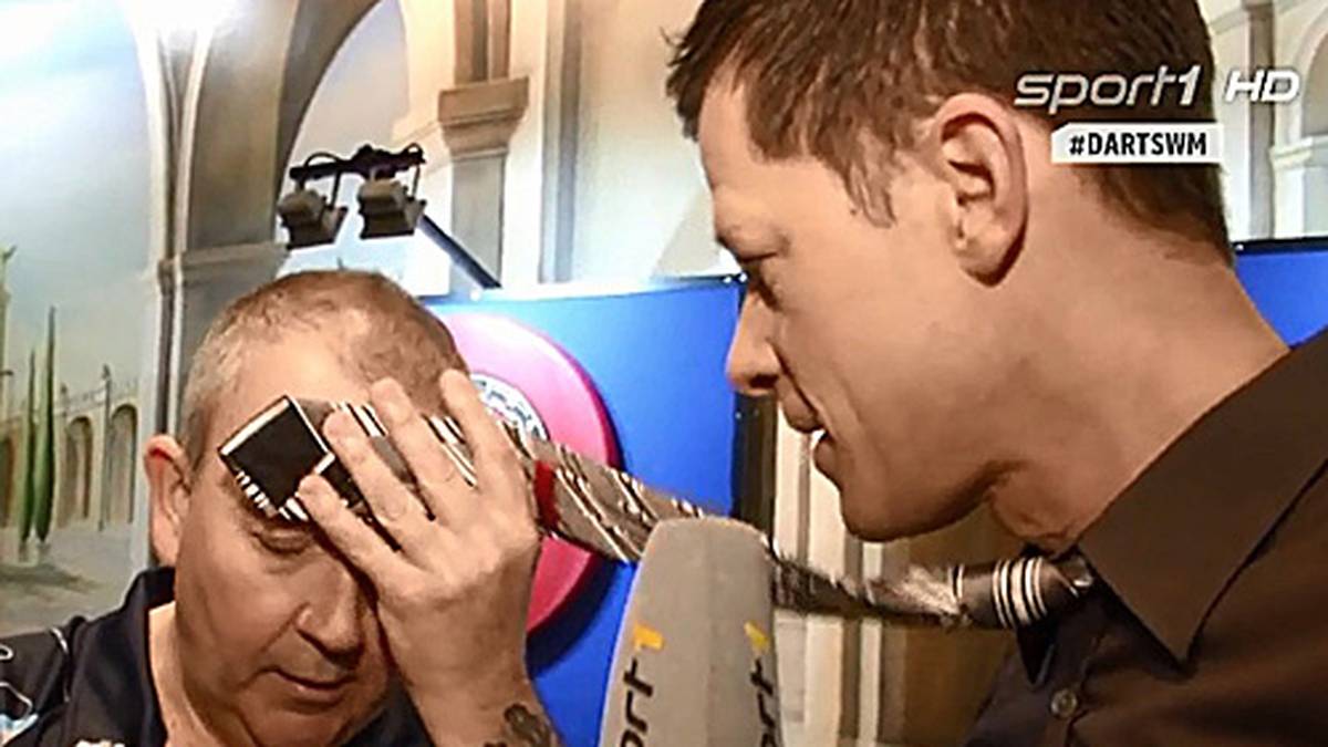 Sein bisher persönliches Highlight bei der WM 2015 erlebt SPORT1-Reporter Sascha Bandermann (r.) beim Interview mit dem mehrfachen Weltmeister Phil Taylor (l.). Der ist vor seinem Viertelfinale gegen Vincent van der Voort offenbar so nervös, dass er sich mit Bandermanns Krawatte erstmal den Schweiß von der Stirn wischt