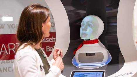 Eine Frau spricht im Reisenzetrum des Hauptbahnhofs mit «Semmi», einem Roboter vom Kundenservice der Deutsche Bahn, der auf Basis Künstlicher Intelligenz (KI) funktioniert.